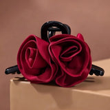 Pince cheveux DoubleRose Couture avec double rose en tissu rouge, posée sur support en studio photo professionnel.