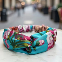 Bandeau cheveux AuroraFlora bleu fleuri présenté sur support en gros plan.