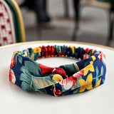 Bandeau cheveux AuroraFlora bleu nuit avec imprimé floral en gros plan sur table.
