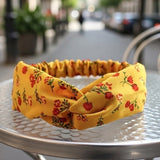 Bandeau cheveux AuroraFlora jaune soleil avec motifs floraux présenté en gros plan sur support.