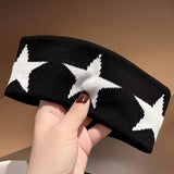 Bandeau cheveux StarPulse noir à étoiles blanches tenu dans la main d’une femme.