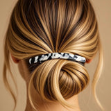 Barrette cheveux blanc et noir maintenant les cheveux enroulés vus de dos.