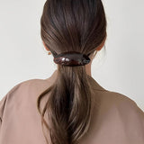Barrette cheveux brun foncé retenant une coiffure arrière.