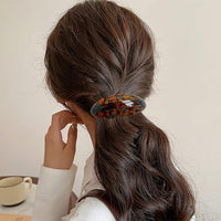 Barrette cheveux brun foncé retenant une coiffure élégante arrière.