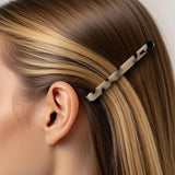 Barrette cheveux marron et noir fixée derrière l’oreille d’une femme élégante.