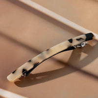 Barrette cheveux marron et noir présentée en studio sur fond luxueux.