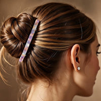 Barrette cheveux en multicolore maintenant les cheveux enroulés d’une femme vue de profil.