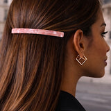 Barrette cheveux rose fixant les cheveux d’une femme sur le côté.