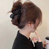 Pince à cheveux WaveSculpt noire en action sur un chignon structuré de cheveux longs féminins.