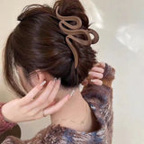 Pince à cheveux WaveSculpt brun foncé tenant fermement les cheveux relevés toute la journée.