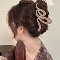 Pince à cheveux WaveSculpt marron clair en action sur cheveux enroulés pour une coiffure élégante et soignée.