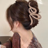 Pince à cheveux WaveSculpt marron clair en action sur cheveux enroulés pour une coiffure élégante et soignée.