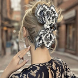 Pince cheveux BandBow maintenant un chignon chic avec motifs paisley noir et blanc.