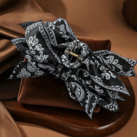 Pince cheveux BandBow noir avec motifs blancs paisley en gros plan studio.