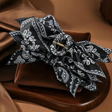 Pince cheveux BandBow noir avec motifs blancs paisley en gros plan studio.