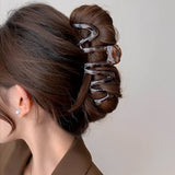 Pince cheveux SpiraHold fixant une coiffure enroulée sophistiquée sur cheveux longs et ondulés.