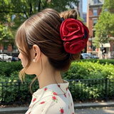 Pince cheveux DoubleRose Couture en rouge ornant un chignon élégant d’une femme urbaine.