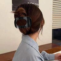 Pince à cheveux GeoFrame maintenant un chignon structuré grâce à sa forme rectangulaire ajourée.