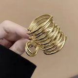 Pince cheveux MetalTwist en métal dorée présentée en gros plan dans la main d’une femme.