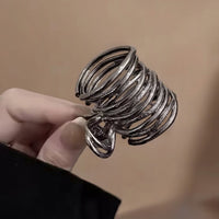Pince cheveux MetalTwist en métal noir tenue en main en gros plan.