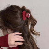 Pince cheveux rouge maintenant les cheveux d’une femme en coiffure haute vue de profil.