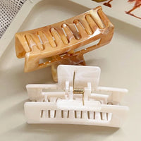 Pince cheveux Soft Hold en lot de 2, couleurs marron et blanc, présentées sur un support blanc pour illustrer leur design et leur usage quotidien.