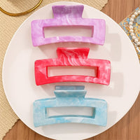 Pince cheveux Soft Hold en lot de 3 couleurs rose, rouge et bleu, disposées sur un support rond blanc pour varier les coiffures avec confort.