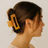 Pince cheveux Soft Hold marron utilisée pour attacher les cheveux sur une tête de femme, offrant une tenue stable sans tirer ni glisser.