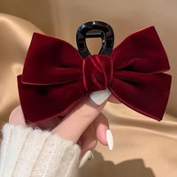 Pince cheveux VelourGrip en velours rouge présentée en gros plan dans la main d’une femme.