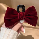 Pince cheveux VelourGrip en velours rouge présentée en gros plan dans la main d’une femme.