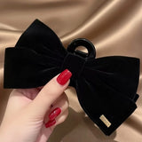 Pince cheveux VelourGrip en velours noir tenue dans la main féminine en gros plan.